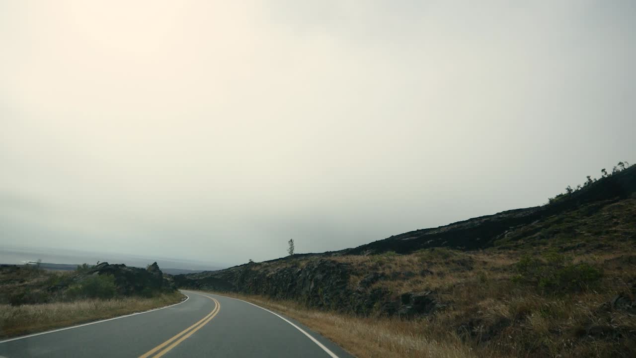 conduciendo desde el cráter de la cumbre de mauna kea en un día nublado con flujos de lava del pasado visibles en las laderas