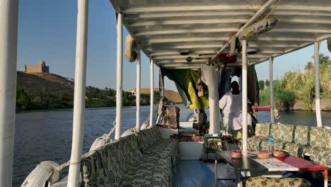 felluca ride on the nile river, overlooking the desert and historic buildings on the banks of the river