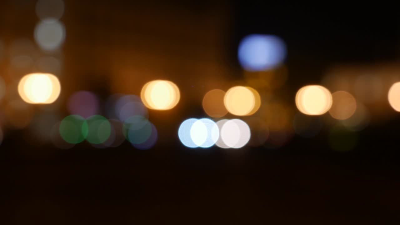 hermoso bokeh brillante en el fondo oscuro borroso por la noche. el redondo bokeh colorido brilla de las luces de los coches en la calle de la ciudad. fuera de foco con borroso. luces de la ciudad sin enfoque. bokeh de tráfico. concepto abstracto
