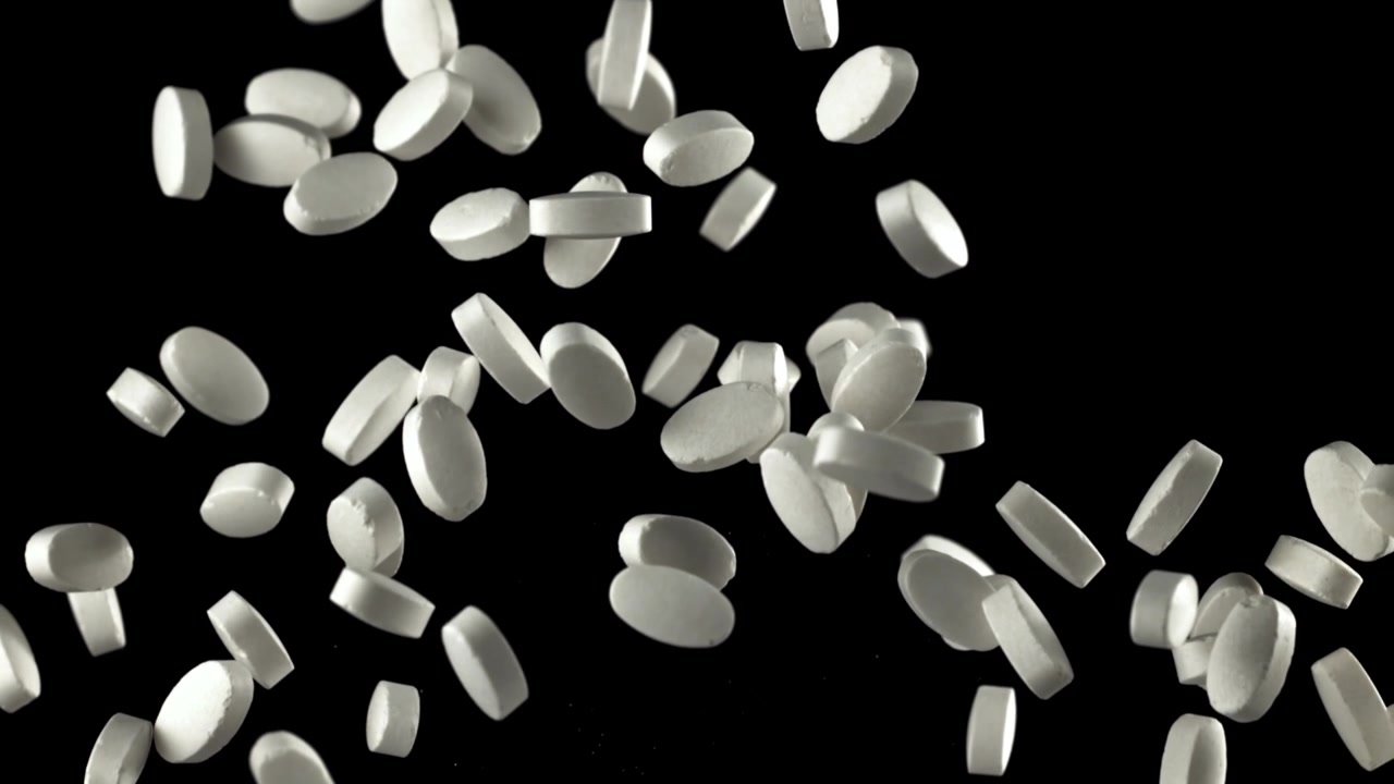 Pillole mediche bianche che cadono al rallentatore su sfondo nero