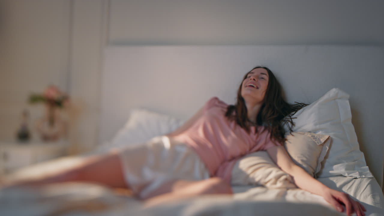 niña despreocupada cayendo en la cama a la luz del sol de la mañana. adolescente feliz y alegre saltando en la cama