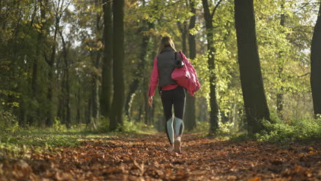 woman walking on a leafy path in an autumn forest