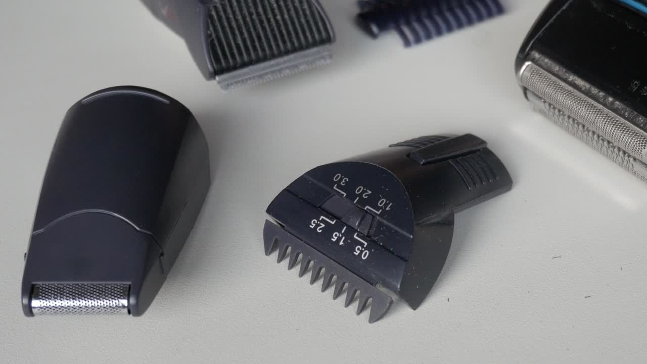 Makro detail elektrického zastřihovače zobrazujícího kryt čepele a texturu plastového těla při neutrálním osvětlení