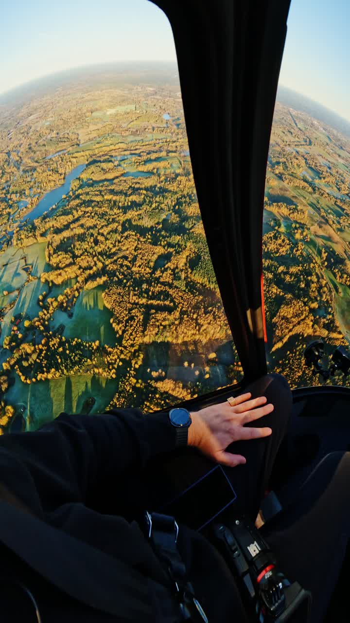 Helicopter cockpit vertical view, golden sunrise over Latvia’s autumn forests