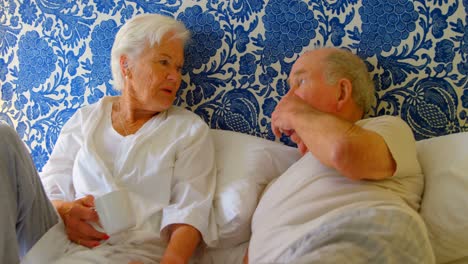 Front-view-of-Caucasian-senior-couple-interacting-with-each-other-on-bed-at-comfortable-home-4k