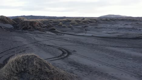 motociclista extremo cruzando dunas de hierba en la playa de arena negra, antena