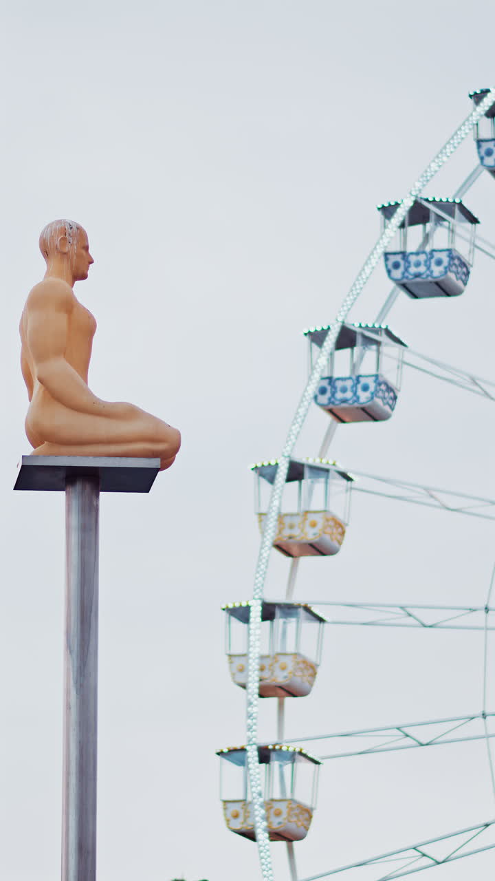 Nice, France - December 8, 2024: Conversation a Nice statue by Jaume Plensa at Place Massena with a ferris wheel on the background. Vertical