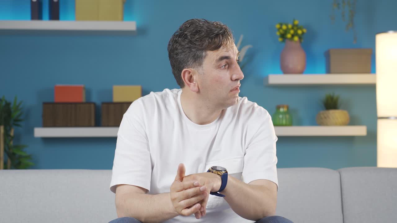 The man waiting for someone at home is constantly looking at his watch.