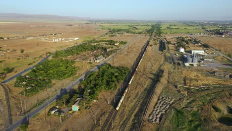 Top-View-Of-A-Train-Departing-On-Railroad-Surrounded-With-Grass-Plains