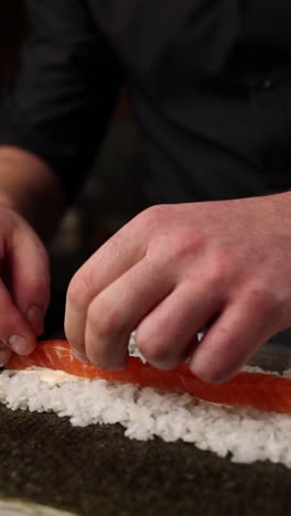 chef haciendo rollos de sushi de salmón