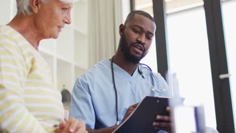 Video-of-african-american-male-doctor-using-tablet-giving-medicines-to-caucasian-senior-woman