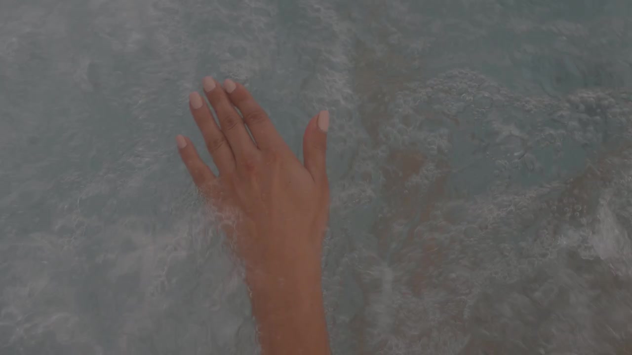Close up of hand moving through bubbling whirlpool water during relaxing thalassotherapy spa session