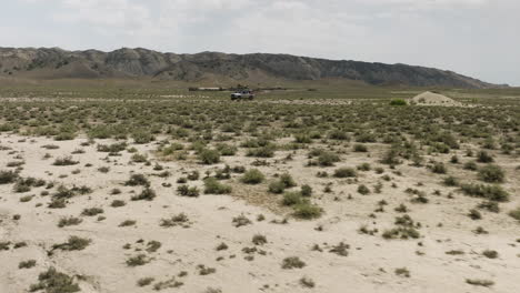 Jeep-parked-in-arid-steppe-plain-in-Georgia,-expedition-camp-behind