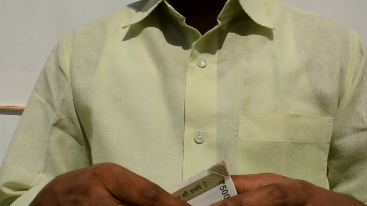 Uomo che conta nuove banconote di valuta indiana.
