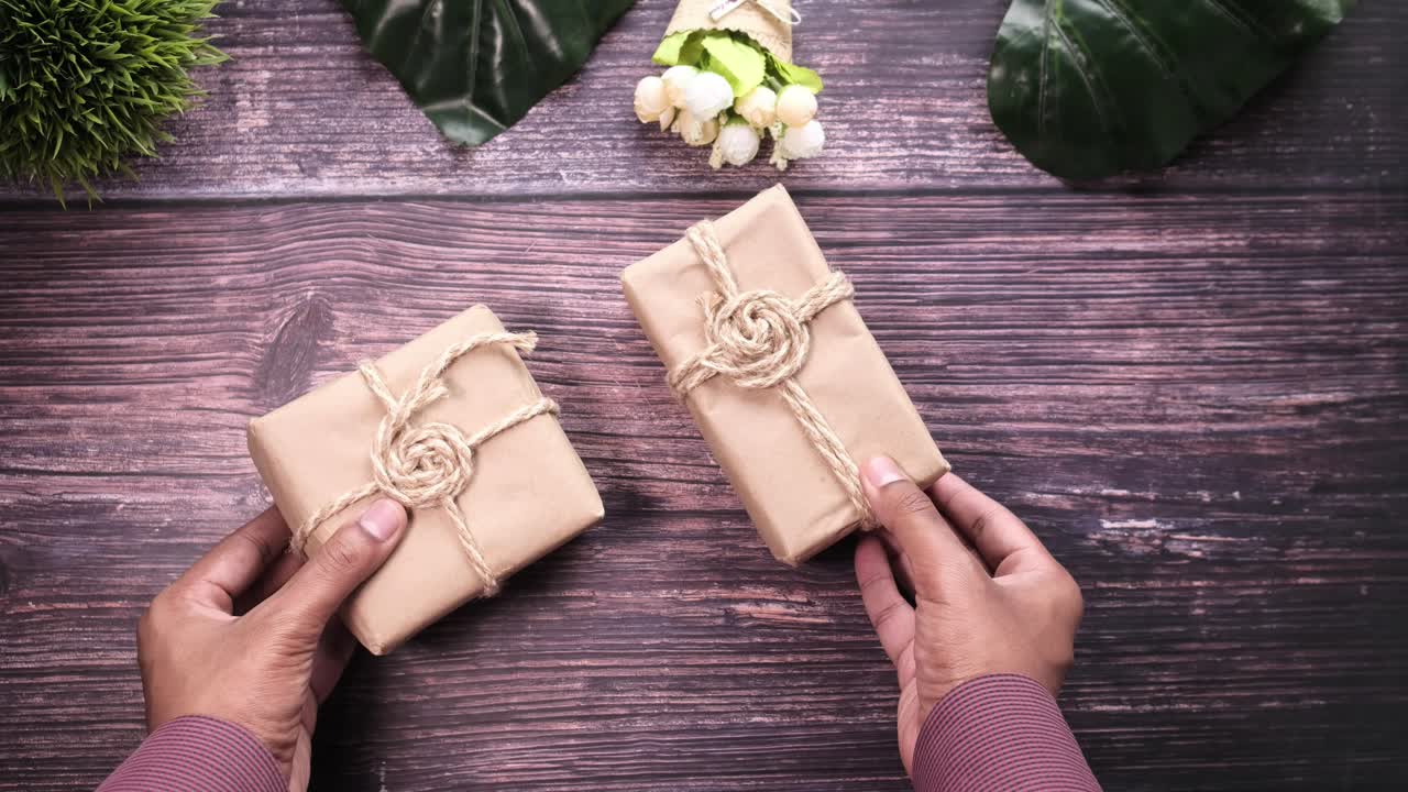 manos sosteniendo regalos envueltos en una mesa de madera