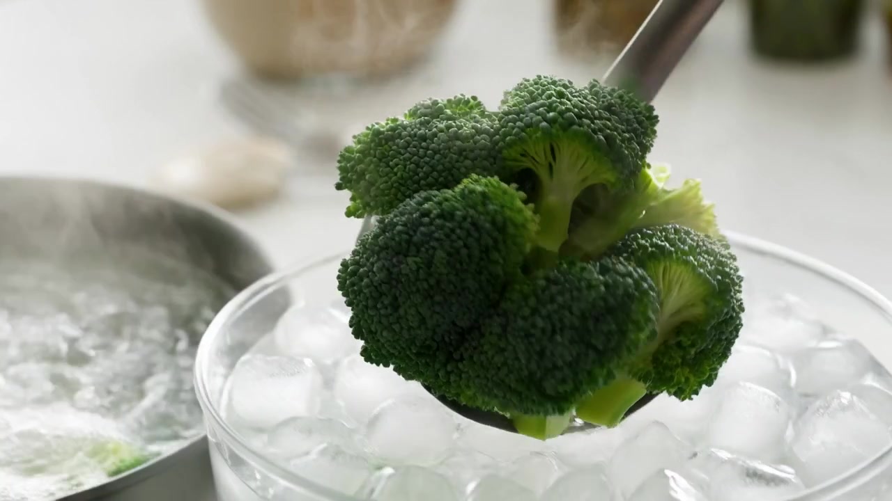 Chef che sbollenta broccoli freschi in acqua bollente e bagno di ghiaccio
