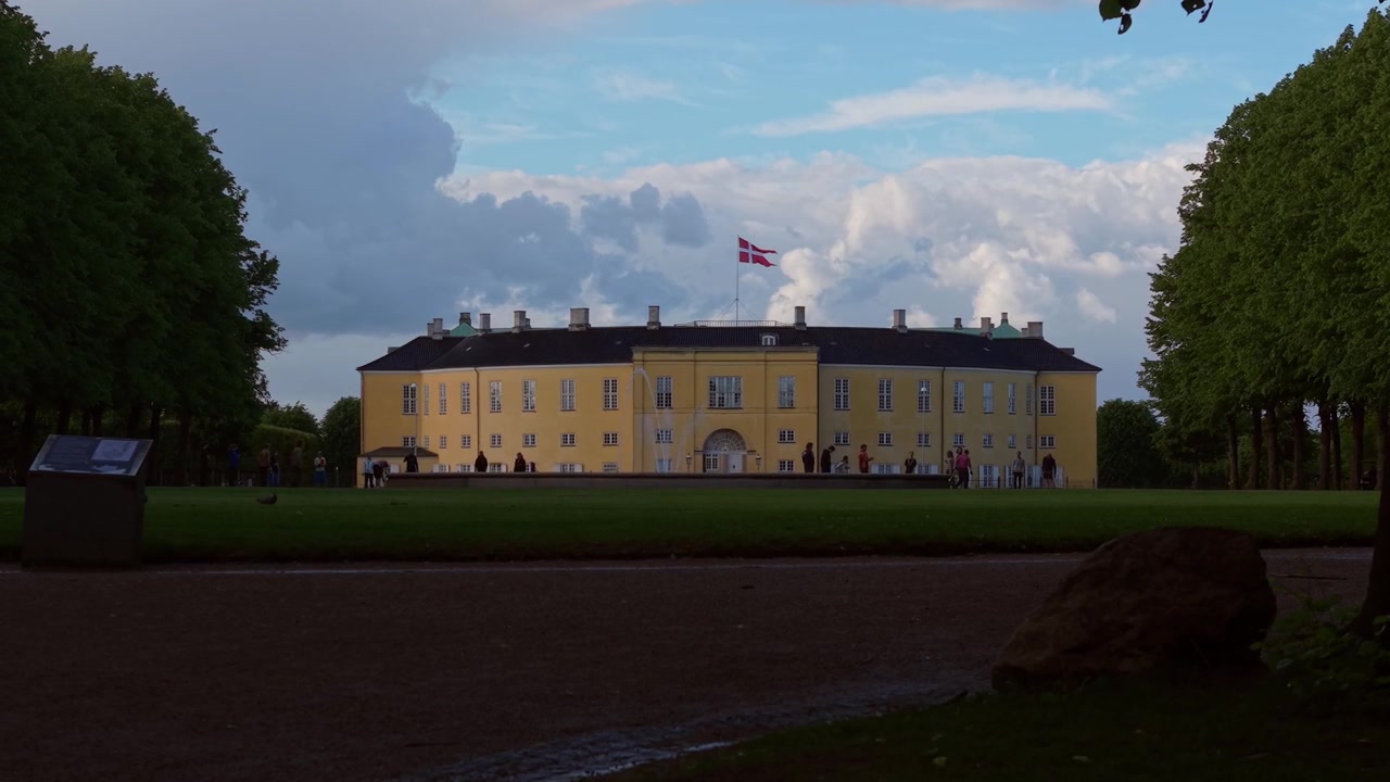 Plano de telefoto da Academia Militar Real Dinamarquesa vista do parque oposto, destacando a elegante arquitetura histórica e os tranquilos arredores verdes.