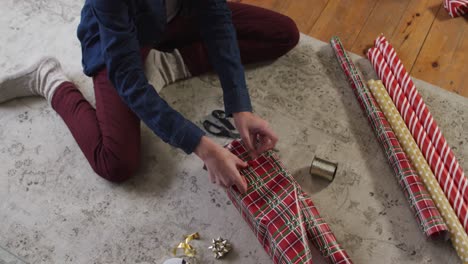 mid section of woman wrapping christmas presents at home