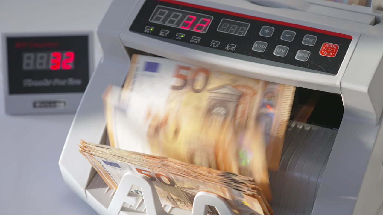 Electronic cash counting machine counts fifty euro banknotes. Figures changing quickly on the counter display at backdrop in blur. Close up.