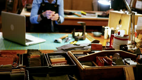 mid-section of craftswoman stitching a piece of leather