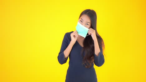 수술용 마스크를 쓴 젊고 예쁜 여자가 코 부분을 조정하고 엄지손가락을 치켜든다