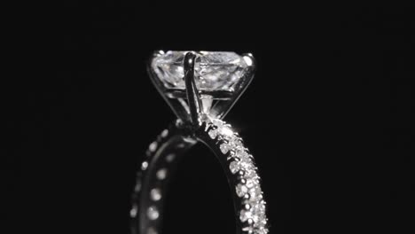 primer plano, anillo de compromiso de diamantes girando sobre fondo negro de estudio