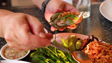 hands preparing oysters with herbs and sauces