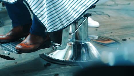 zapatos marrones del hombre de cerca sentado en la silla de peluquería. equipo de barbero