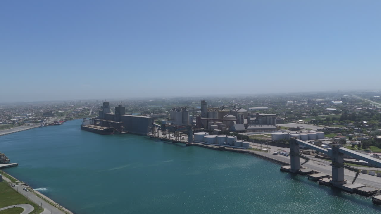 una toma aérea cinematográfica que muestra el puerto de necochea y el río quequén grande, destacando el pintoresco río, el bullicioso puerto y el paisaje natural circundante en argentina.