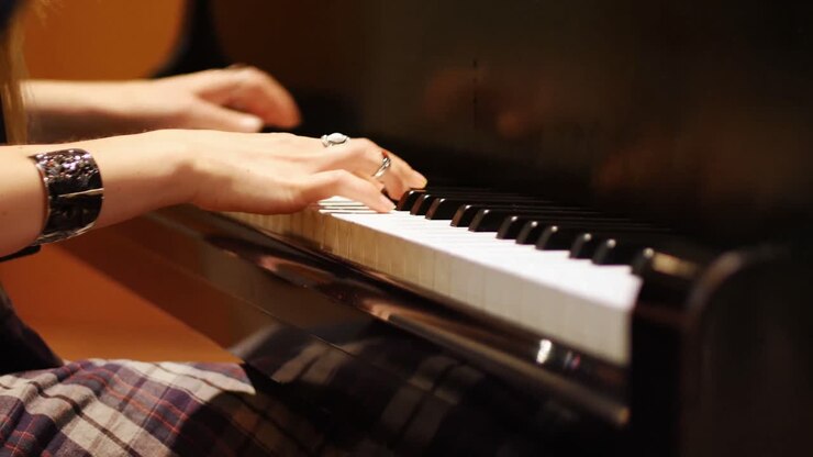 Keskivartalokuva naisesta soittamassa pianoa.