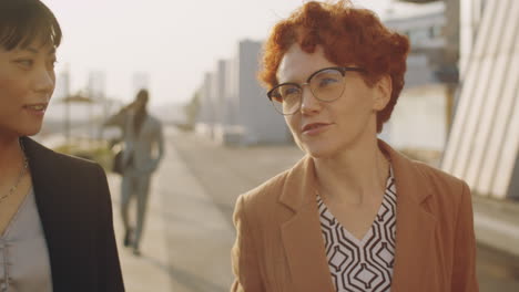 asian and caucasian businesswomen walking outdoors and talking