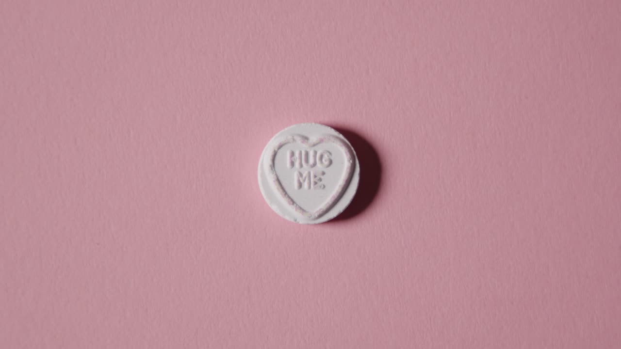 분홍색 배경에 나를 안아줘 메시지와 함께 심장 사탕을 손에 들고