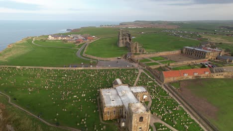 historic saint mary's church with whitby abbey ruins in the distance in north yorkshire, england