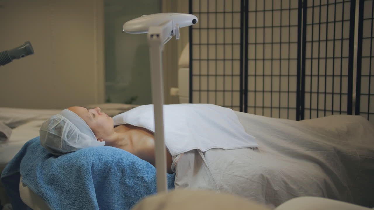 피부 관리 미용 치료를 받는 동안 침대에 누워 있는 여성, 와이드 샷