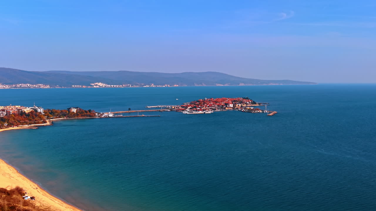 Veduta aerea distante di una città storica su una penisola e di una spiaggia sabbiosa. Scatto grandangolare di una città antica su una penisola che si estende nel mare con una spiaggia in primo piano.