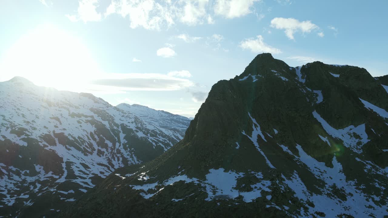Majestætiske sneklædte bjerge, klar sol skaber lens flare over barske tinder, Italienske Alper, Italien. Panoramisk droneudsigt fra luften