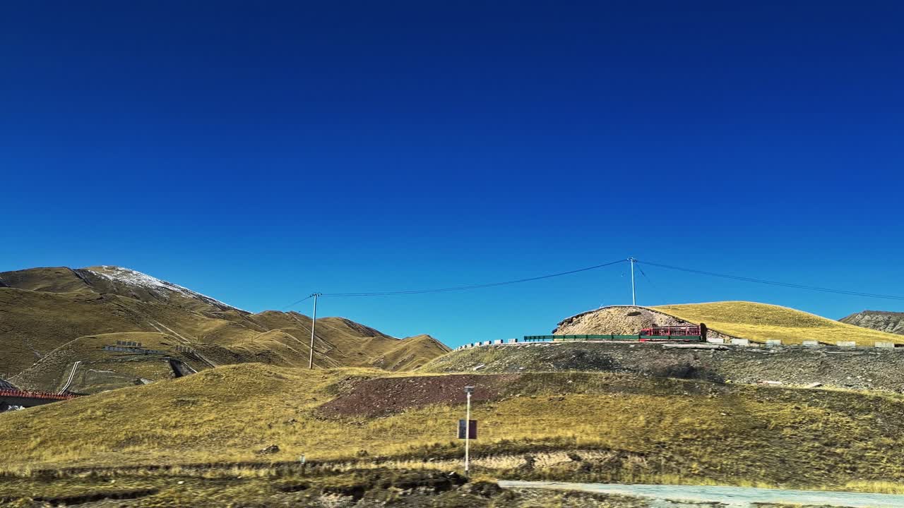 Along the Way, Qinghai and Gansu Province, China - A Lone Red Truck Drives Along a Winding Mountain Road Under a Clear, Vivid Blue Sky - POV Shot