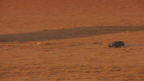 zoom hacia atrás para revelar un camión beduino conduciendo rápido a través de las vastas arenas del desierto de wadi rum jordania