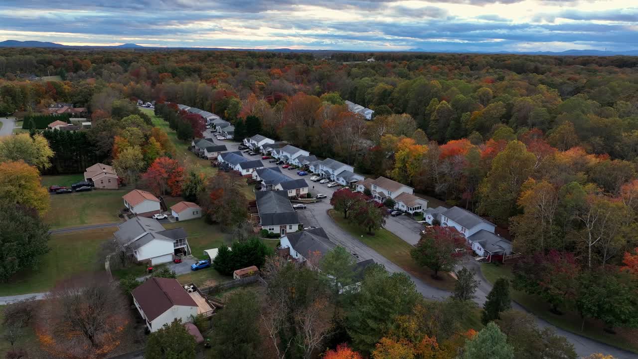 Small american community neighborhood in usa with row of houses. Cloudy morning in quiet suburbia of city. Colored trees on autumnal day. Virginia, America. Drone approaching shot
