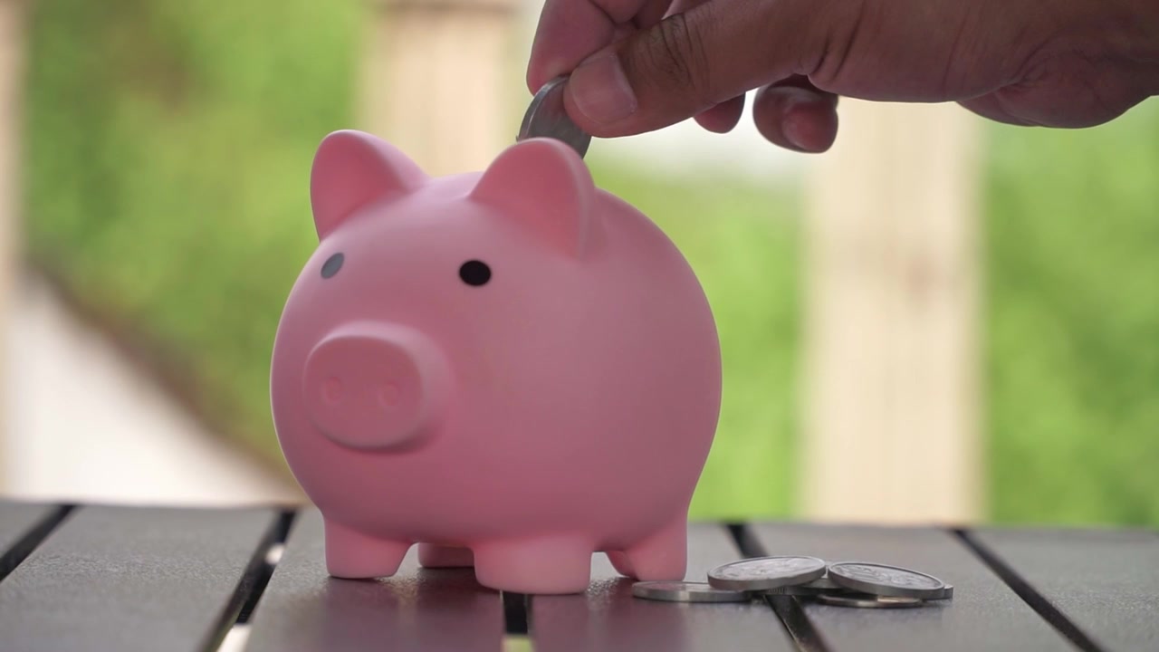 Saving coins in a pink piggy bank, finance and investment concept for economic growth. Close-up of piggy bank with coins,