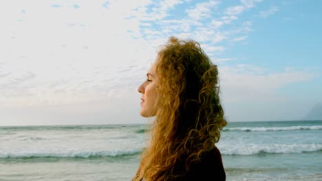 mujer caucásica joven pensativa de pie en la playa en el sol 4k