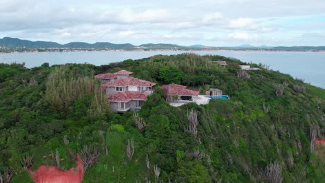 fly over the top of a mountain with a mansion with a pool in búzios, brazil