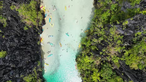 aerial top down above tourists relaxing in beach hidden between el nido cliffs