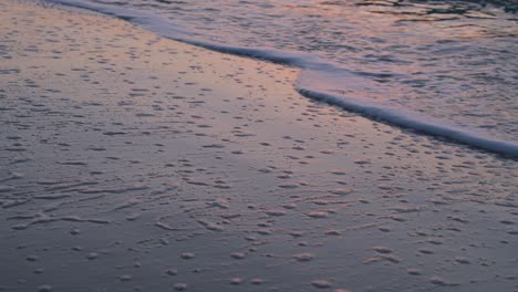 olas de mar tranquilas que llegan a la playa de arena creando textura con espuma de mar blanca