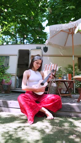 woman playing ukulele on a campsite