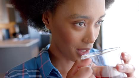 happy african american woman drinking tea in sunny kitchen, in slow motion