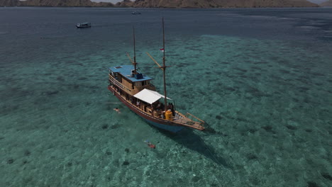Luftaufnahme-Eines-Touristen,-Der-Um-Das-Holzboot-Im-Indonesischen-Ozean-Herumschwimmt