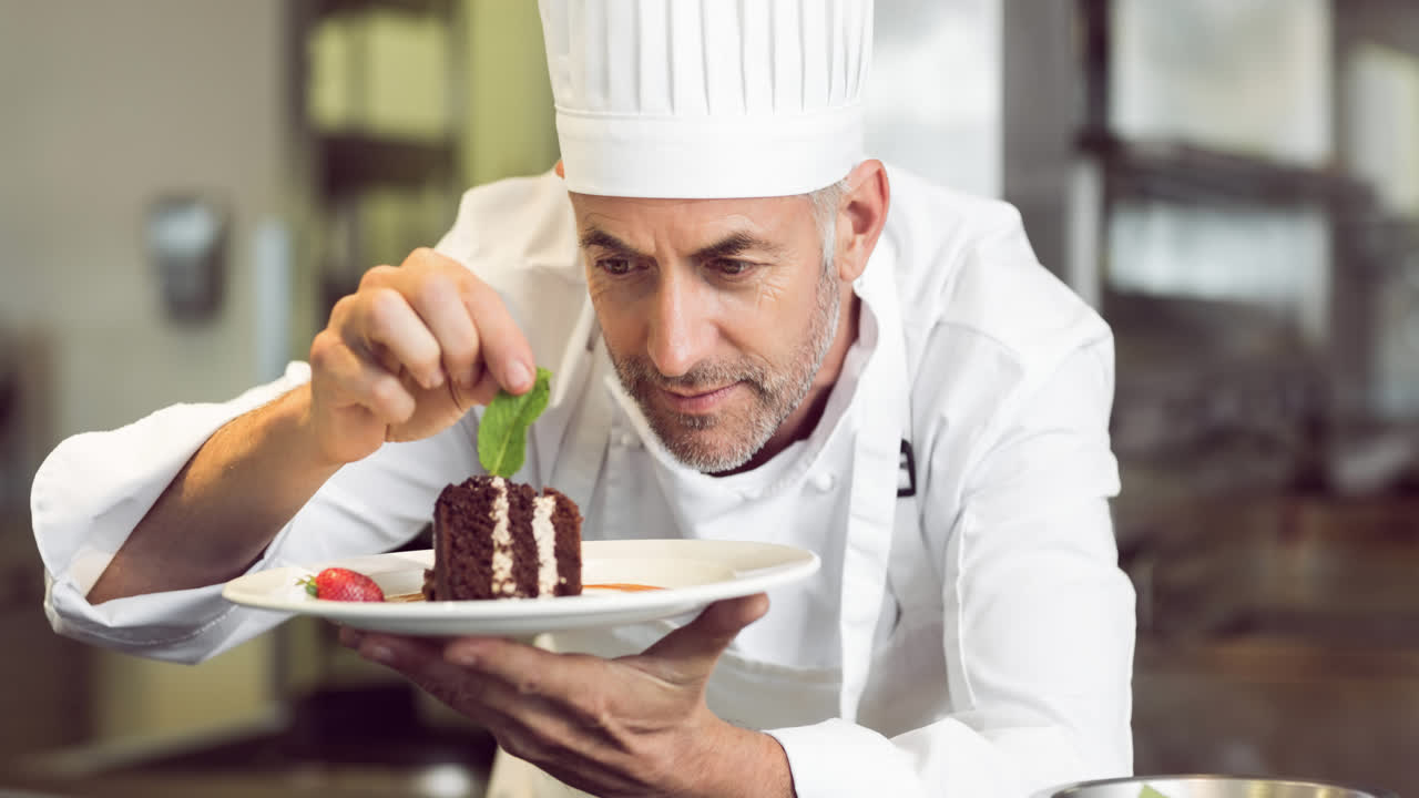 un chef caucásico sonriente con un delantal preparando comida en una cocina profesional