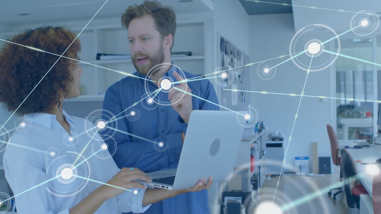 Man pointing at laptop while woman listening in tech office, displaying network node overlay