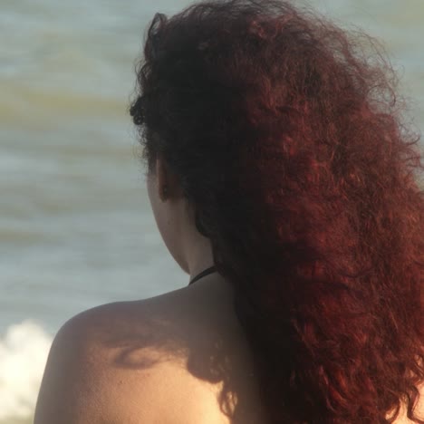 woman with red curly hair at the beach